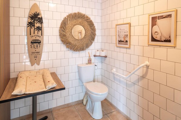 A bathroom with a toilet, a sink, a mirror, and a surfboard decoration. - Sure Hotel by Best Western Mont-de-Marsan (Saint-Pierre-du-Mont)