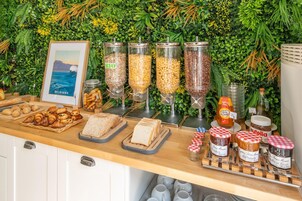 Un bufé con diversos alimentos, incluyendo pan, pasteles y salsas.