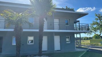 A two-story building with a balcony, palm trees, and a clear sky.