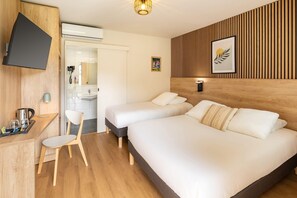 Habitación de hotel con dos camas, un escritorio con una silla, un televisor montado en la pared y un diseño de paneles de madera en la pared.