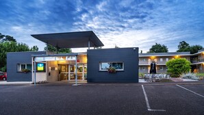 Un hotel moderno con entrada cubierta, asientos al aire libre y estacionamiento.