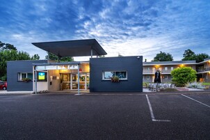 Un hotel moderno con entrada cubierta, asientos al aire libre y estacionamiento.