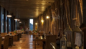 A restaurant with wooden floors, tables, and chairs. There are hanging lights and a sign on the wall.