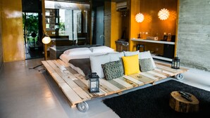 A modern bedroom with a wooden platform bed, a black rug, and a small wooden stool.