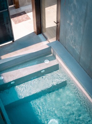 A clear view of a swimming pool with steps leading into it, a tiled floor, and a door leading to an adjacent room.