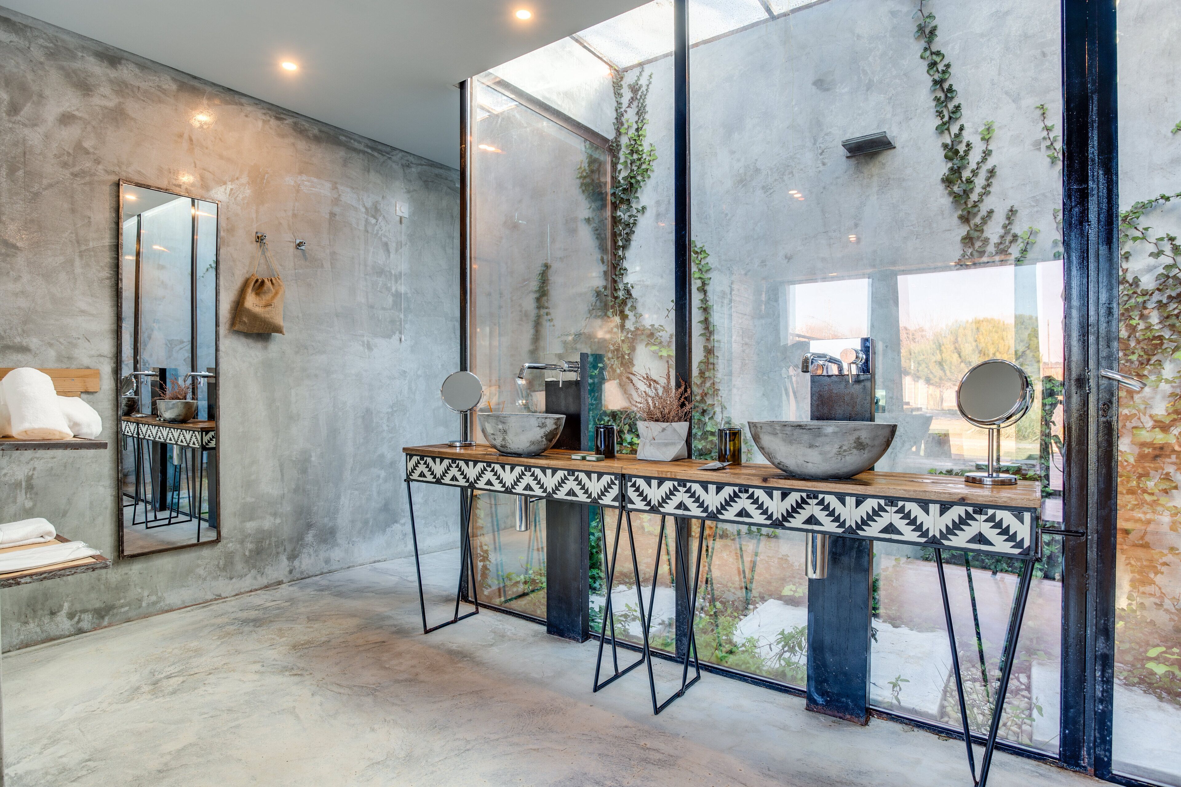 Un baño moderno con un espejo grande, dos lavamanos y una mesa decorativa.