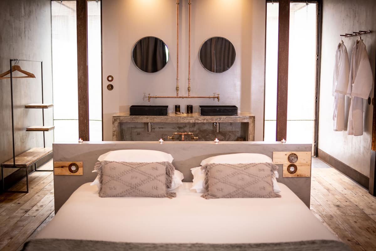 Ein modernes Badezimmer mit einem großen Spiegel, zwei Waschbecken und einem Holzlagerfläschchen.