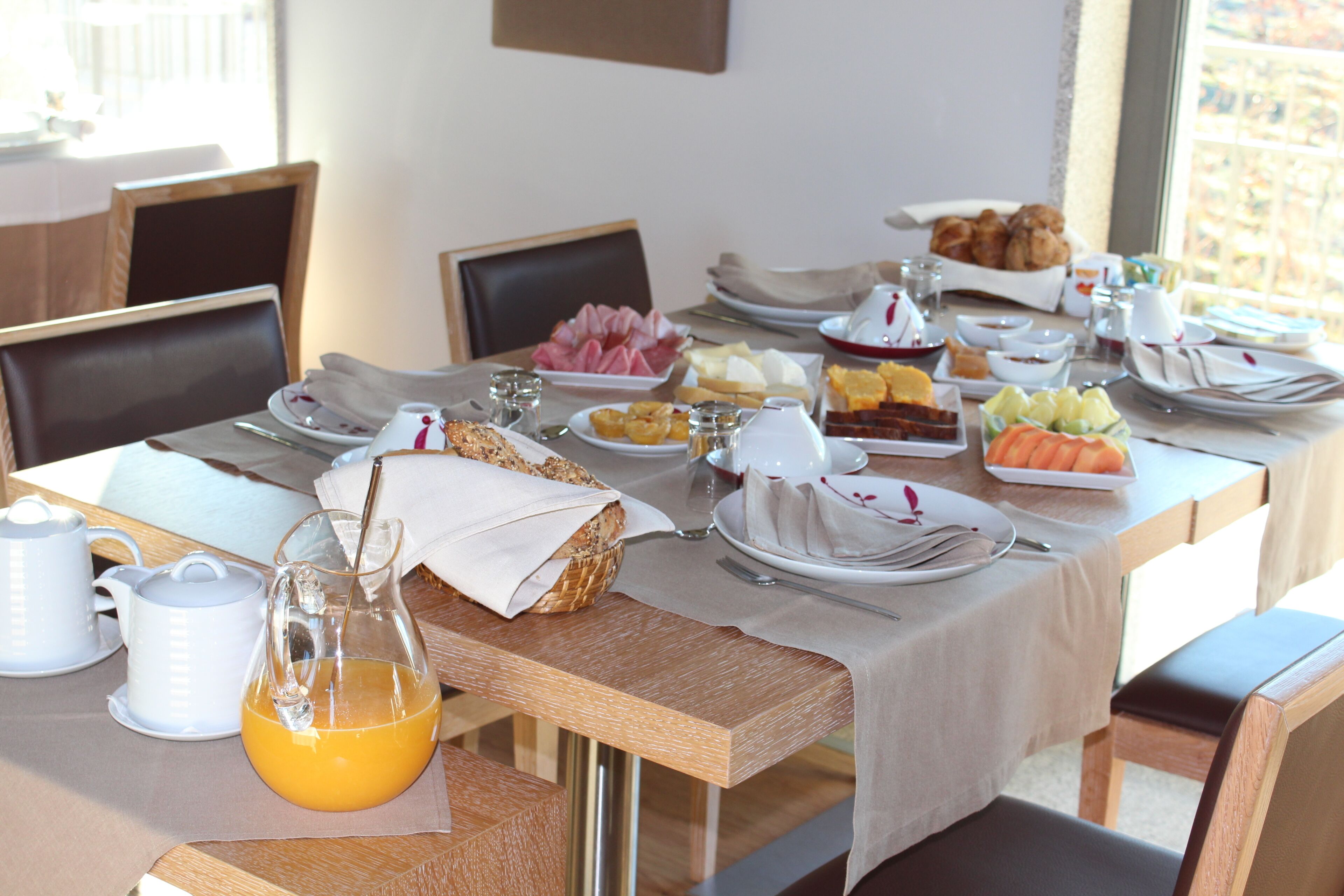 Una mesa de desayuno preparada con diversos alimentos, como pasteles, frutas y bebidas.
