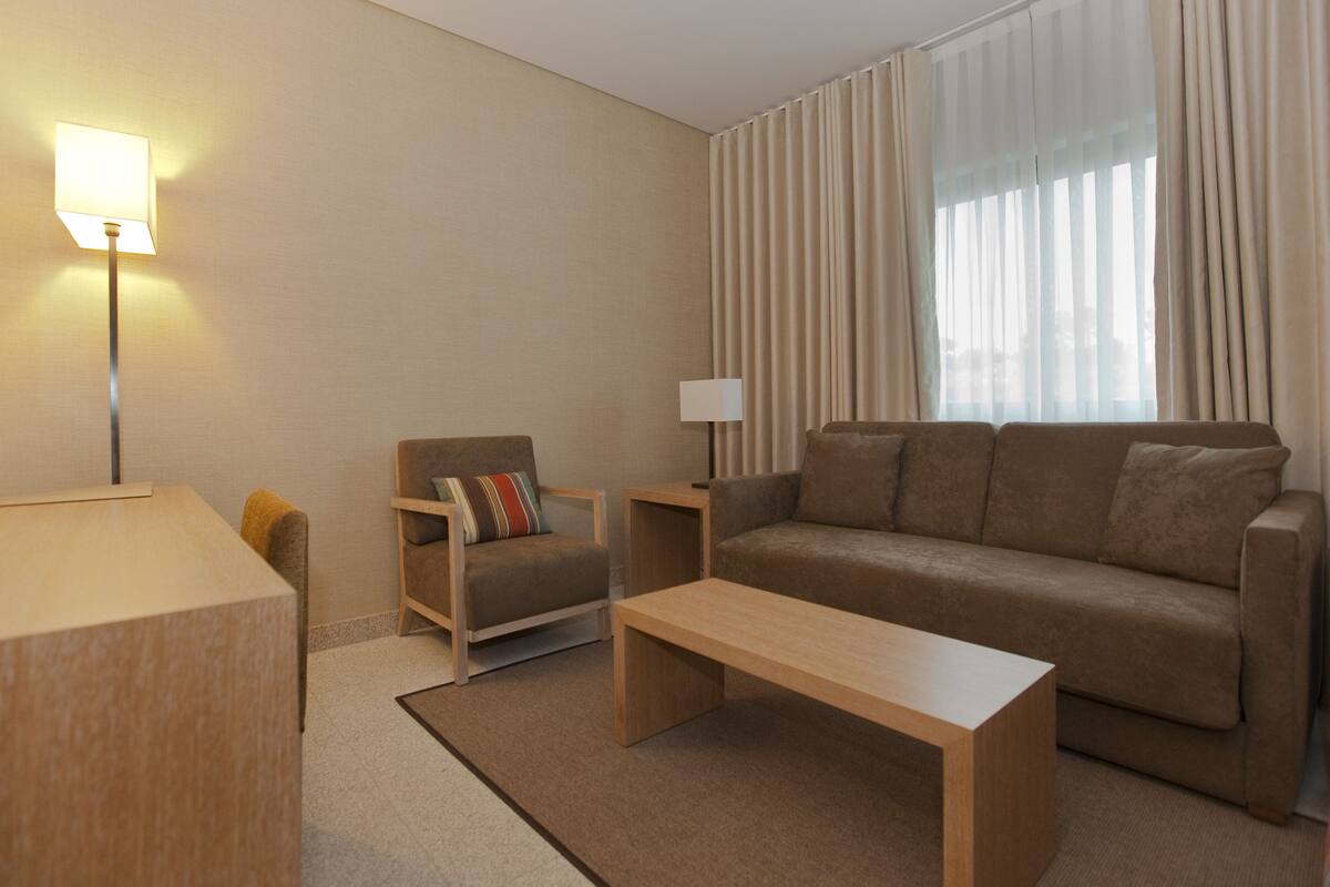 A modern living room with a sofa, armchair, coffee table, and lamp.