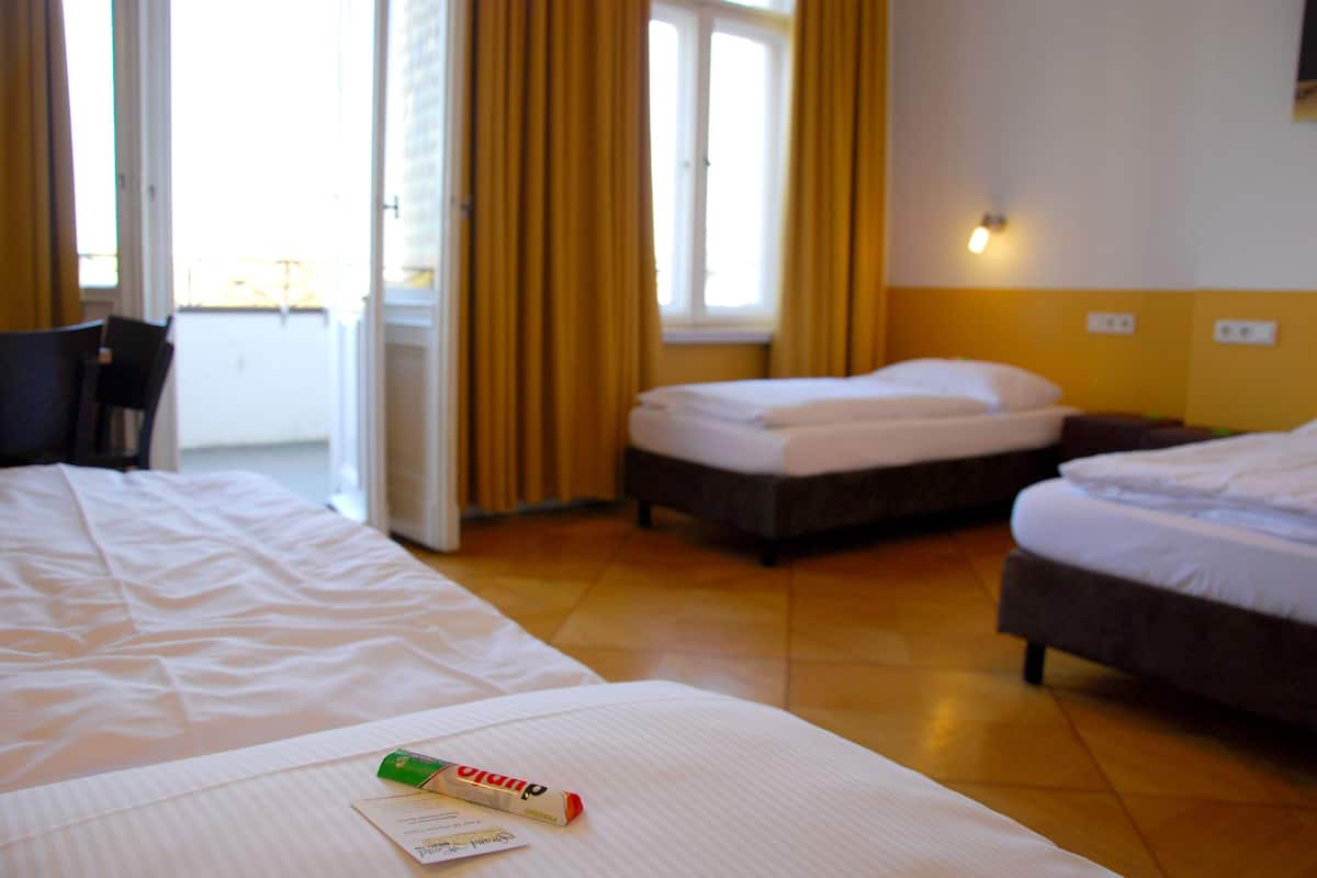 A hotel room with two beds, a window with curtains, and a bedside table with a tissue box.