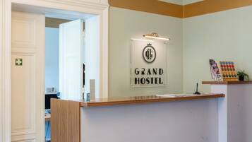 Ein Empfangsbereich mit einem Schild, auf dem 'Grand Hostel' steht, und einer darüber hängenden Chandeliebre.