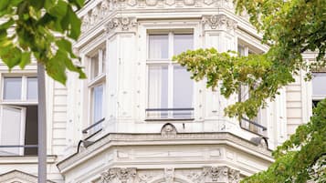 Un edificio en esquina con detalles arquitectónicos ornamentados, ventanas grandes y un balcón.
