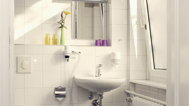 Un baño moderno con lavamanos, espejo y retrete blancos.