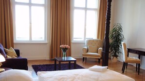 A well-lit room with a large window, a chair, a small table with a vase of flowers, and a bed with pillows. - Grand Hostel Berlin Classic (Berlin)