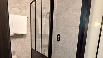 A modern bathroom with a glass-enclosed shower, a toilet, and a towel rack.