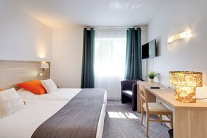A hotel room with two beds, a desk, a chair, a TV, and a lamp. - Brit Hotel Le Cygne (Saint-Hilaire-du-Harcouet)