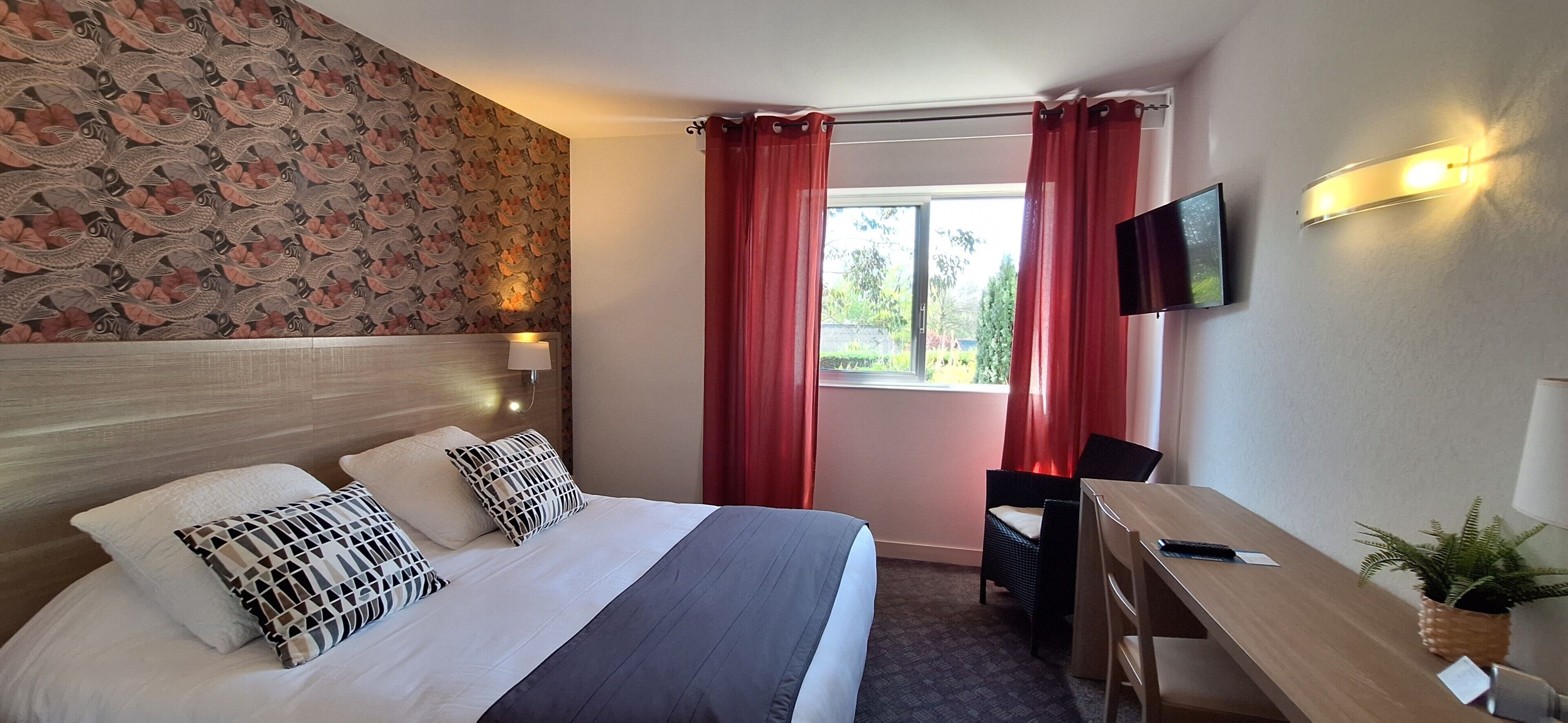 A hotel room with a bed, a desk, a chair, a TV, and a window with curtains.