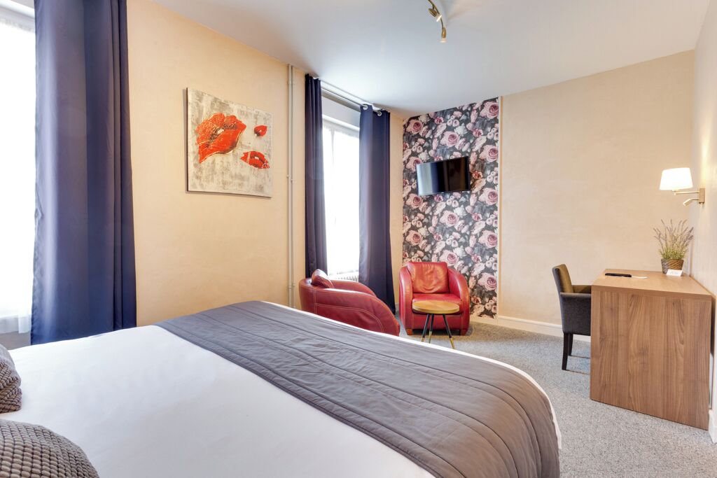 Une chambre d’hôtel avec un grand lit, un bureau, une chaise et une petite table.
