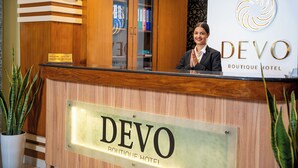 Un comptoir d'accueil avec une enseigne indiquant « DEVO Boutique Hotel ».