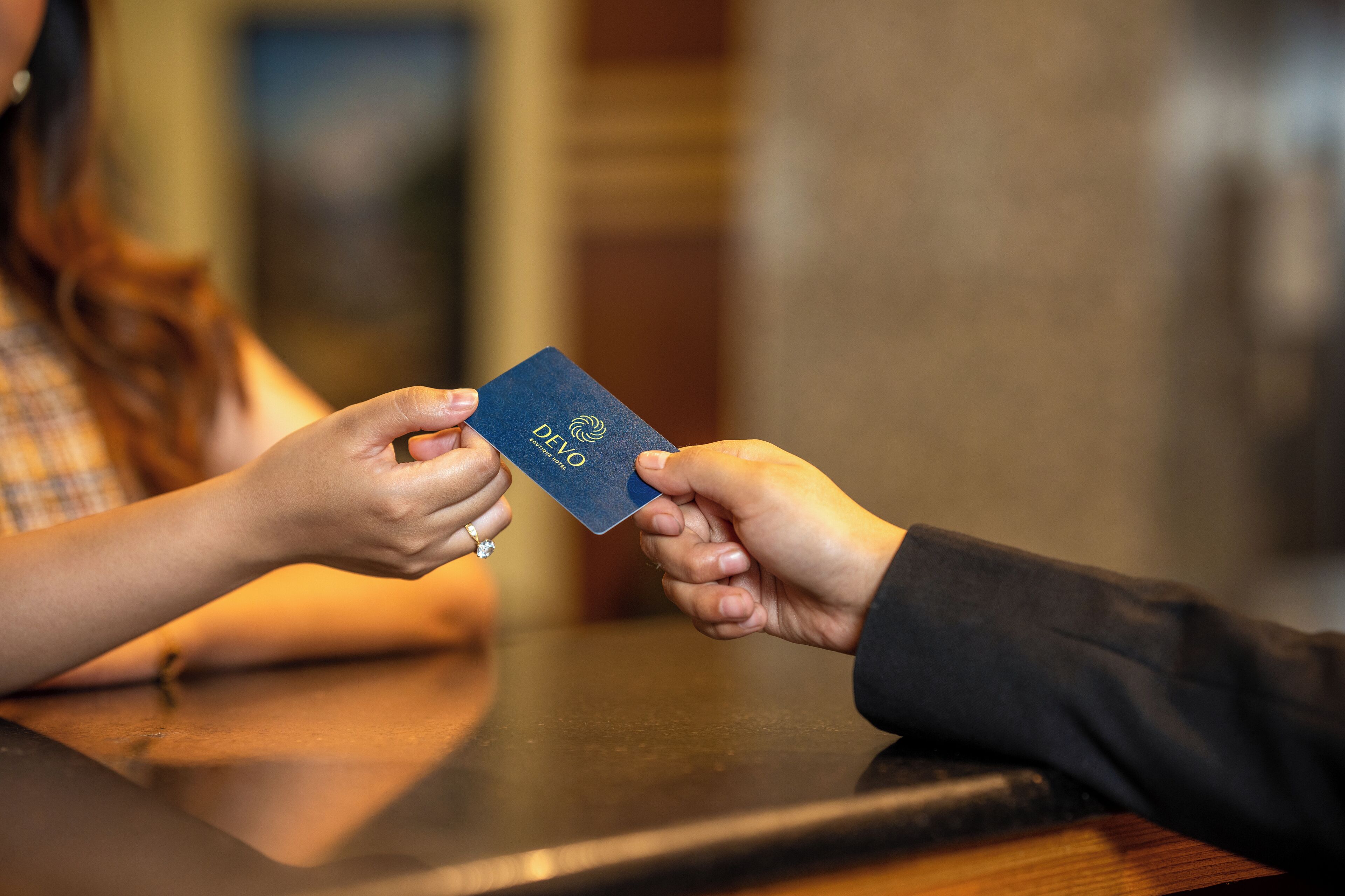 A person handing over a blue passport to another person at a table.