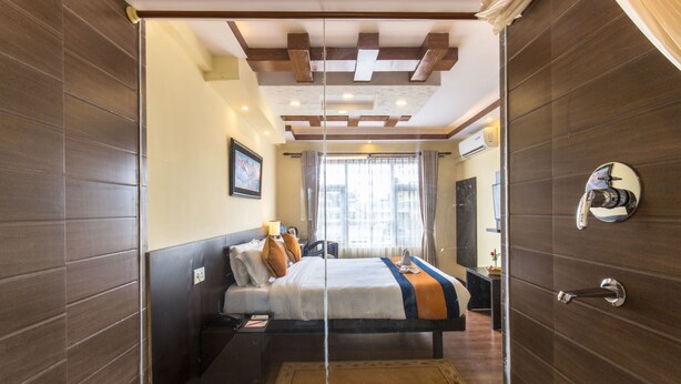 Une chambre d’hôtel moderne dotée d’un grand lit, d’une paroi en verre et d’une vue sur la ville.