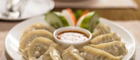 A plate of dumplings with a dipping sauce, accompanied by a salad and a plate of vegetables.