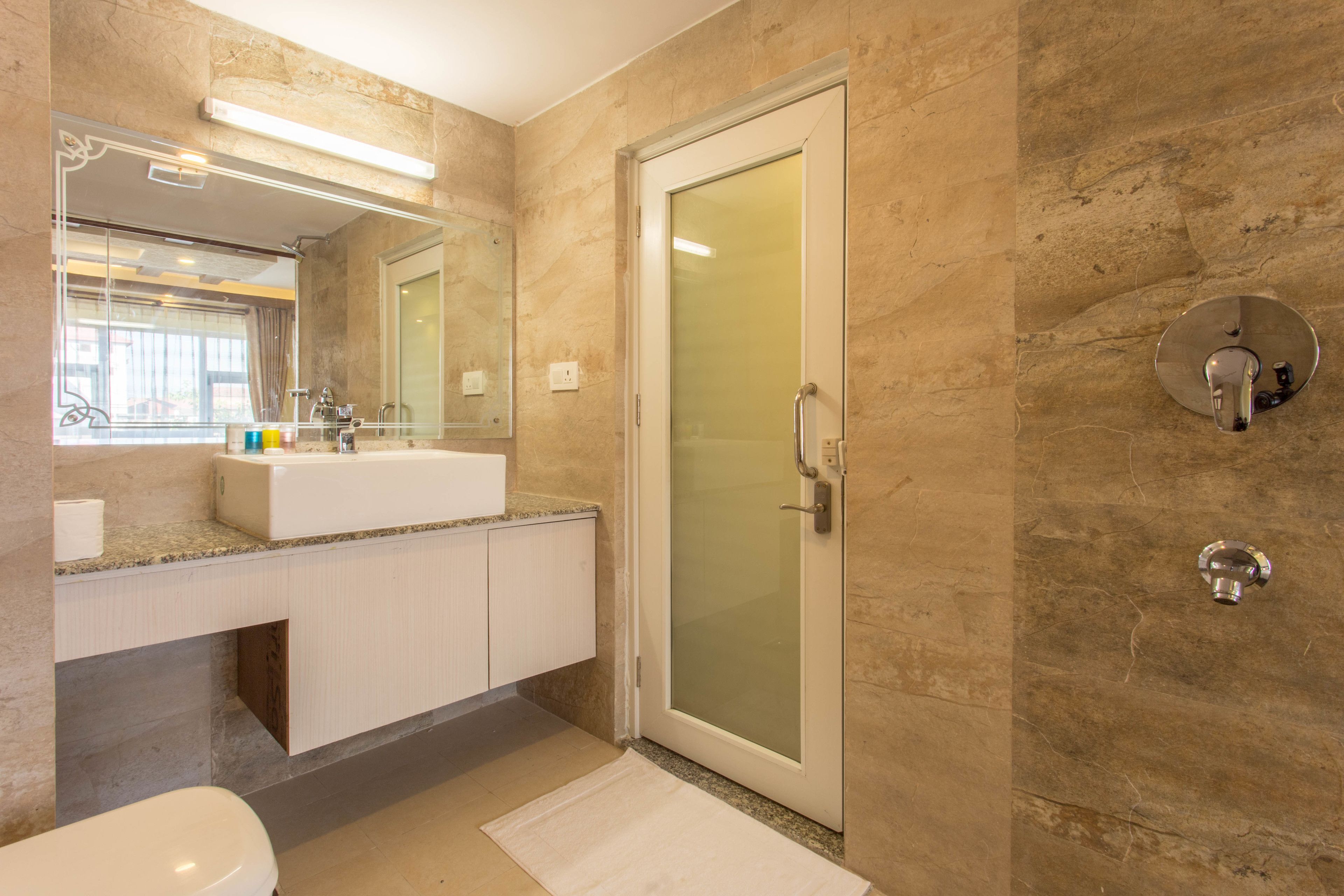 A modern bathroom with a glass-enclosed shower, a white sink, and a large mirror.