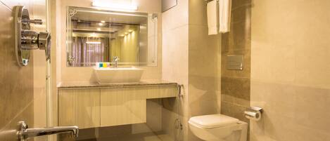 Un baño moderno con cabina de ducha de vidrio, inodoro, lavabo con espejo y toallero con toallas.