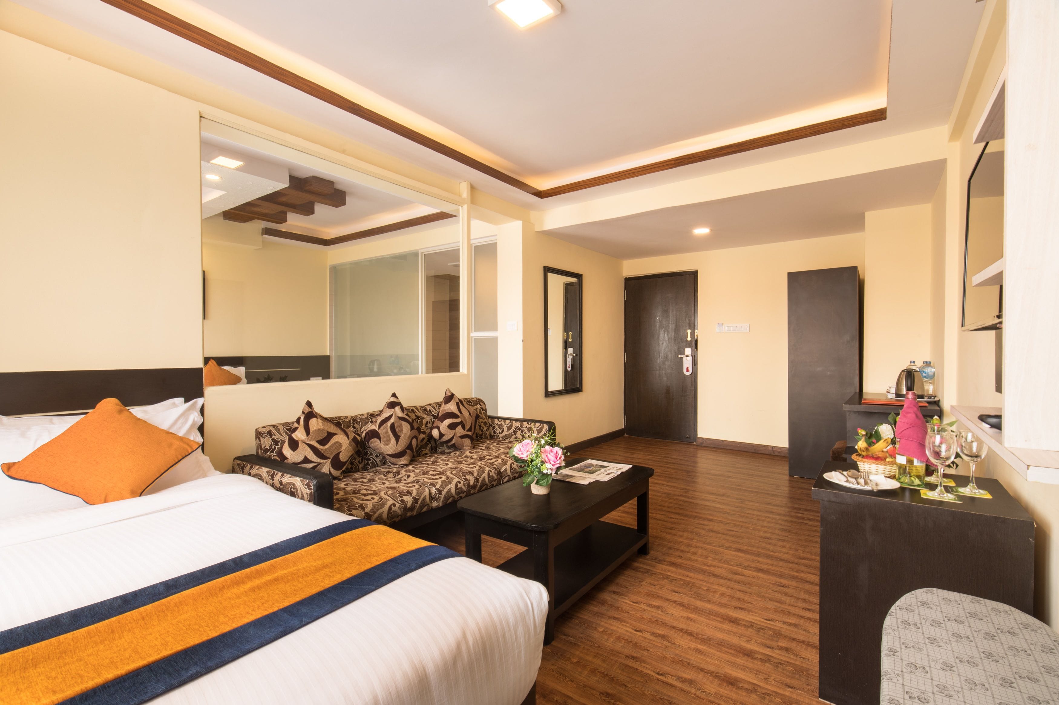 A hotel room with a bed, a sofa, a coffee table, and a desk with a mirror.