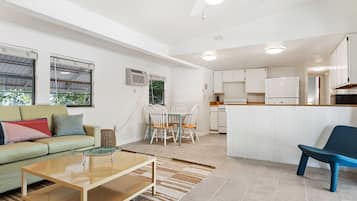 Ein modernes Wohnzimmer mit einer Couch, einem Couchtisch und einem Essbereich mit Stühlen.