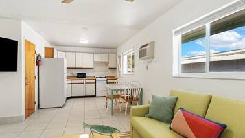 A compact living space with a kitchenette, a dining area, and a sofa with colorful cushions.