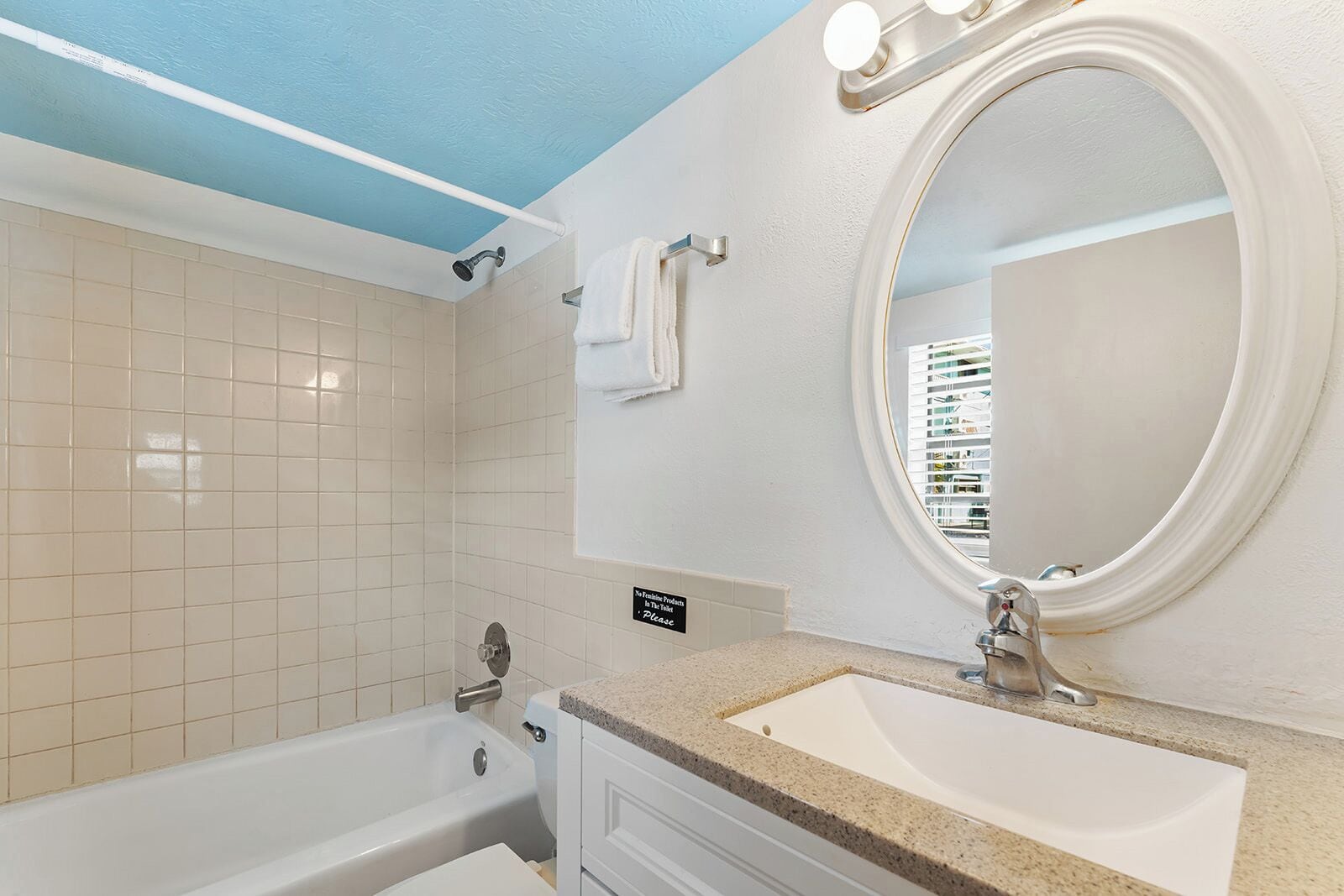 Un baño con bañera, lavabo, espejo y toallero.