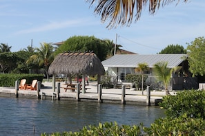 Relax by the water's edge in this serene waterfront retreat, featuring a thatched-roof gazebo and a dock.
