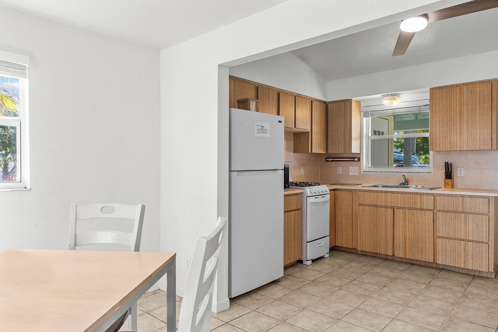 A compact kitchen with wooden cabinets, a white refrigerator, a stove, and a sink.