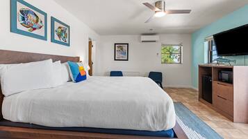A bedroom with a bed, a ceiling fan, a TV, and artwork on the walls.