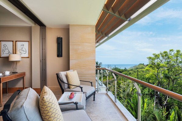 A balcony with a sofa, a table with a tray of fruit, and framed artwork.