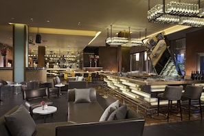 A modern bar area with seating, a bar counter, and a unique light fixture.