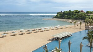 A beach resort with a swimming pool, beach chairs, and umbrellas. - Mulia Resort (Nusa Dua)