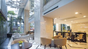 A modern lobby with seating areas, a reception desk, and a view of the outside.