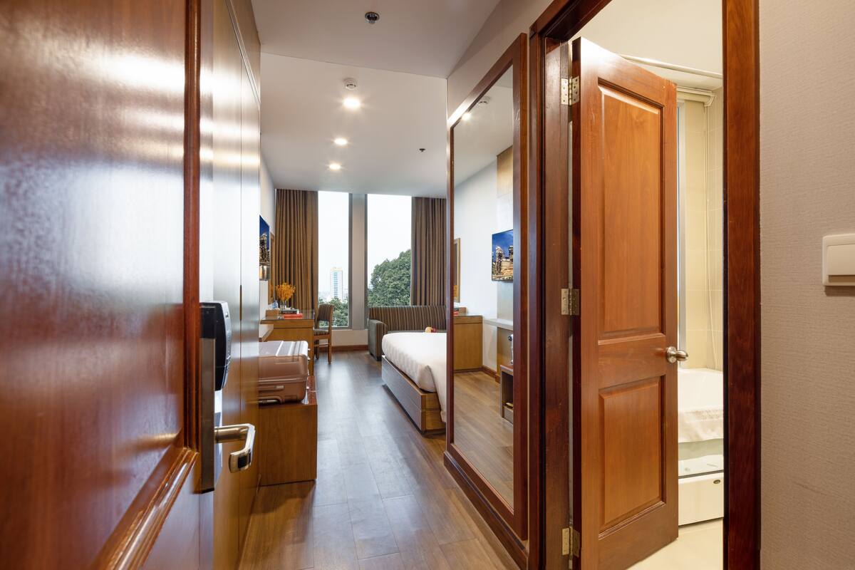 Une chambre d’hôtel avec un plancher en bois, un lit, un bureau et une chaise.