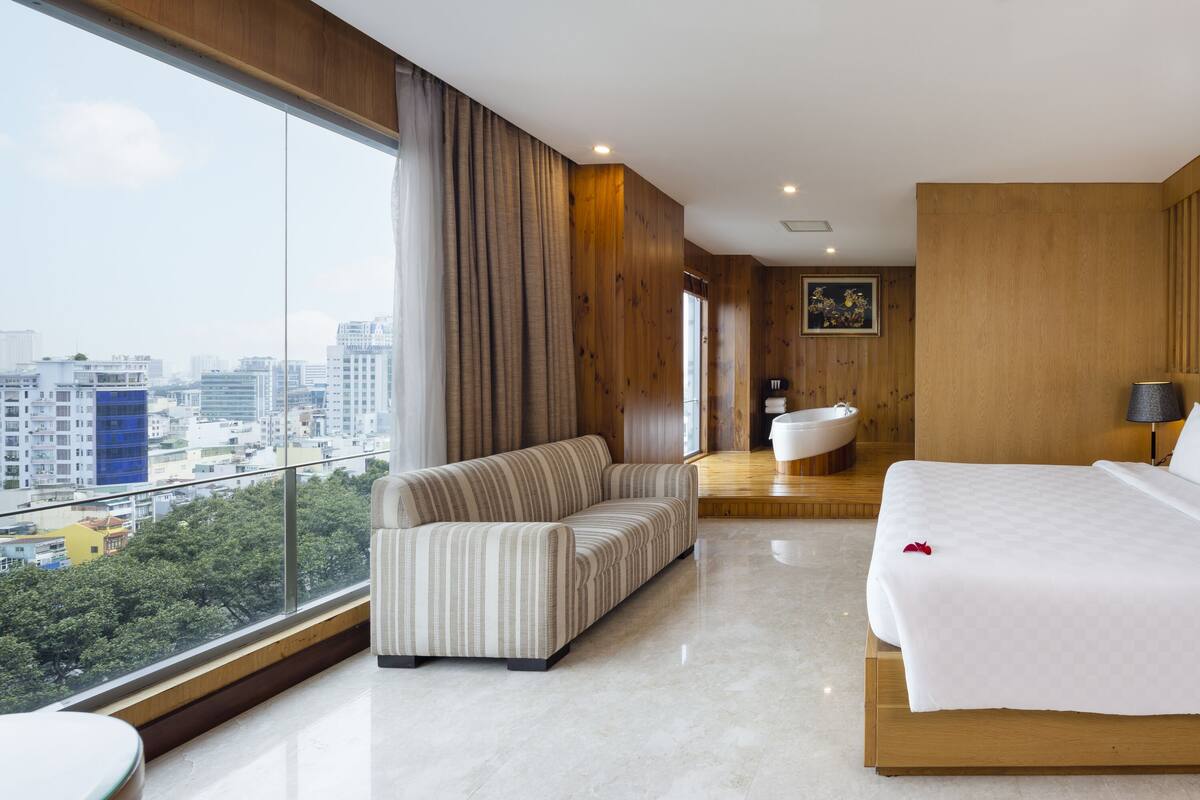 Une chambre d’hôtel moderne dotée d’un grand lit, d’un canapé, d’une salle de bain et offrant une vue sur la ville.