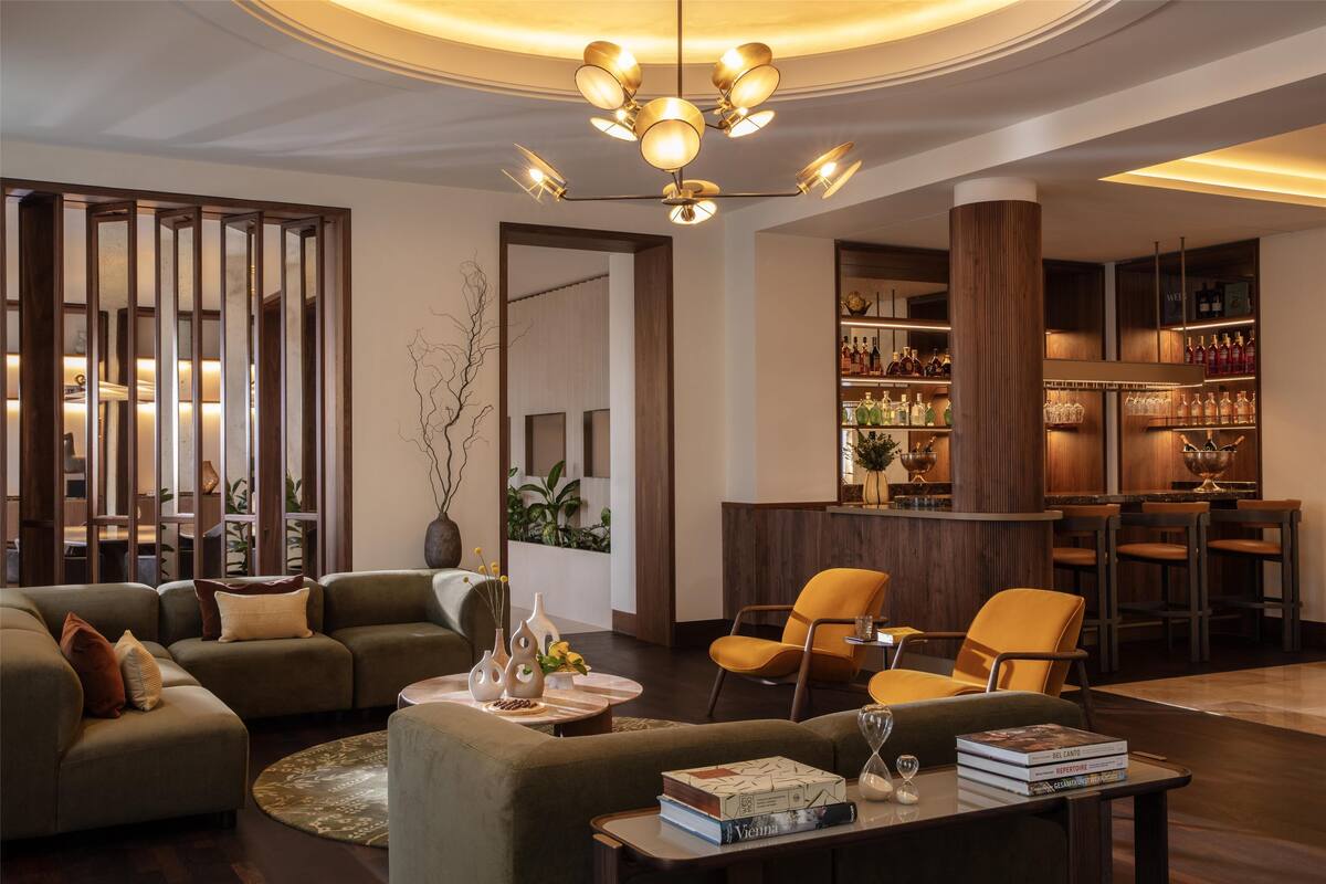 Ein modernes Wohnzimmer mit einer Couch, Sesseln, einem Couchtisch und einem Bücherregal.