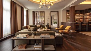 A modern living room with a sectional sofa, a coffee table, and a bar area with stools. - Anantara Palais Hansen Vienna – A Leading Hotel of the World (Vienna)