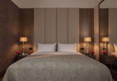 A hotel room with a large bed, two bedside tables with lamps, and a mirror on one wall.
