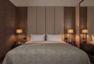 A hotel room with a large bed, two bedside tables with lamps, and a mirror on one wall.