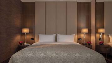 A hotel room with a large bed, two bedside tables with lamps, and a mirror on one wall.