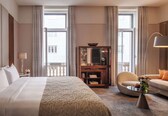 A hotel room with a large bed, a desk, a sofa, and a small table with flowers.