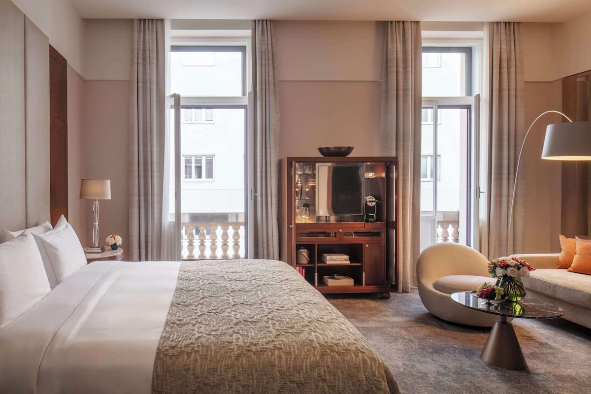 Ein Hotelzimmer mit einem großen Bett, einem Schreibtisch, einer Couch und einem kleinen Tisch mit Blumen.