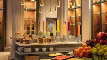 A buffet with various food items and a fruit bowl.
