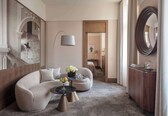 A modern hotel lobby with a curved sofa, a round coffee table, and a floor lamp.